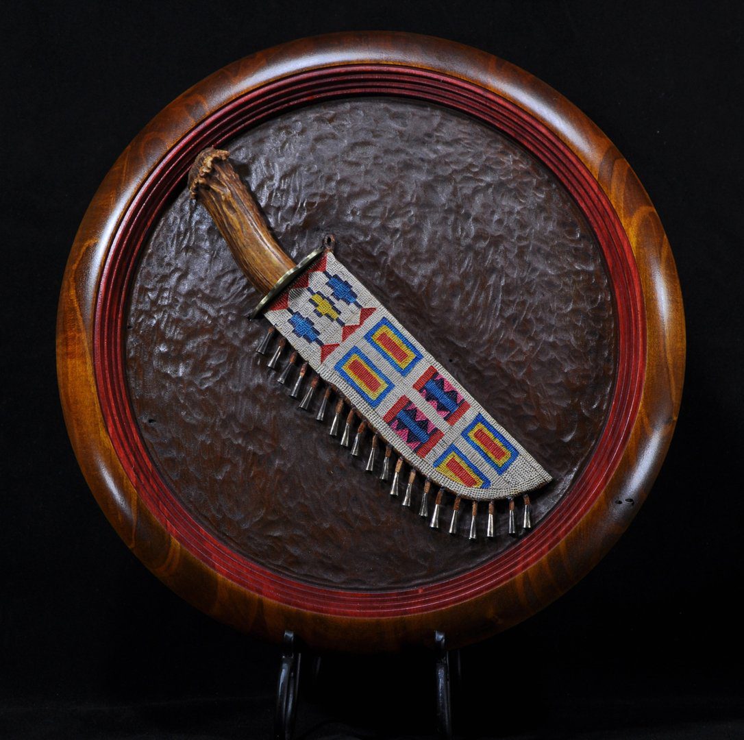 A knife with colorful designs on it is sitting in a wooden frame.