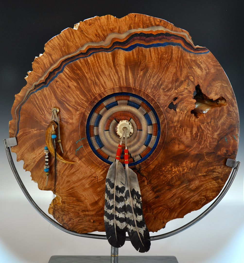A wooden fan with feathers on top of it.