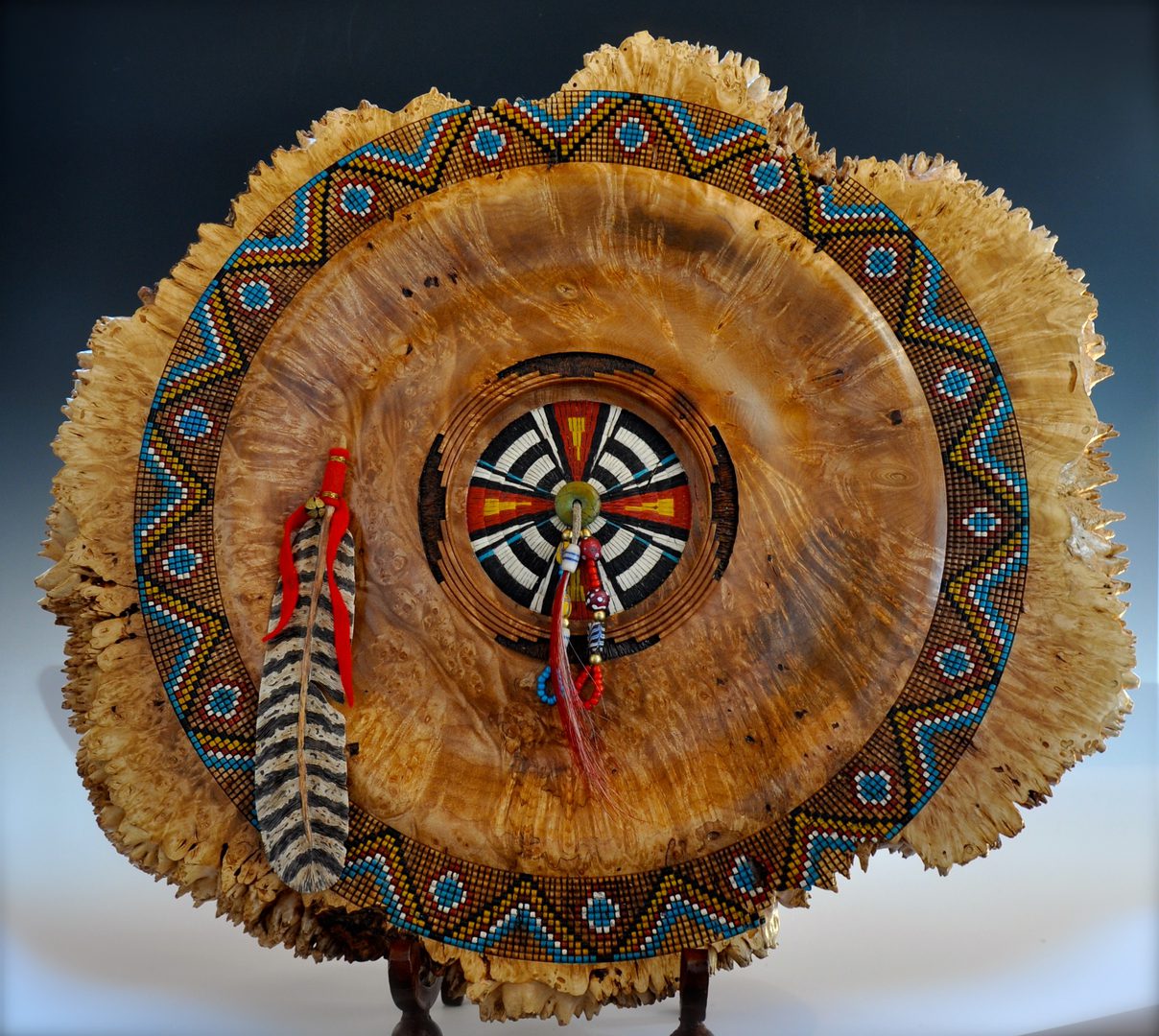 A wooden plate with feathers and beads on top of it.