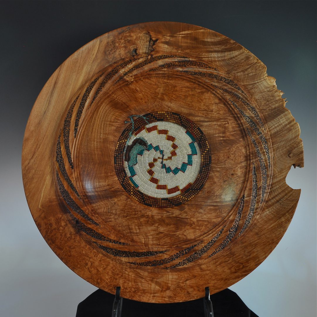 A wooden bowl with a spiral design on it.